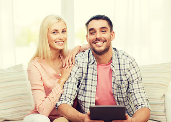 smiling happy couple with tablet pc at home