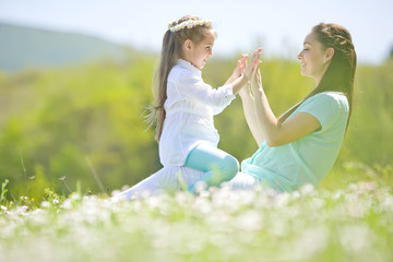 Mother with kid are resting on the nature on camomile field