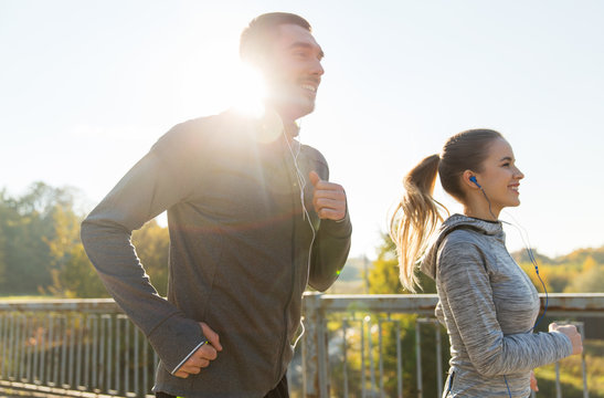 happy couple with earphones running outdoors