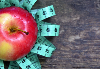Fresh apple and measuring tape on wooden background.Healthy eating or diet concept. 