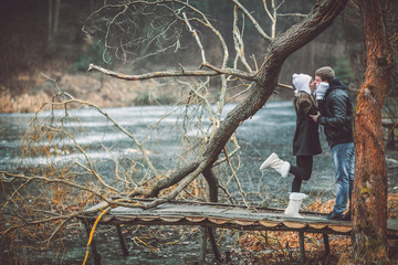 Beautiful young couple posing near lake and forest autumn. Woman in white gloves and cap.