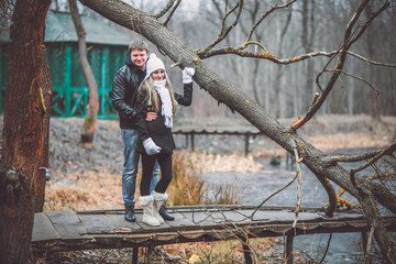 Beautiful young couple posing near lake and forest autumn. Woman in white gloves and cap.