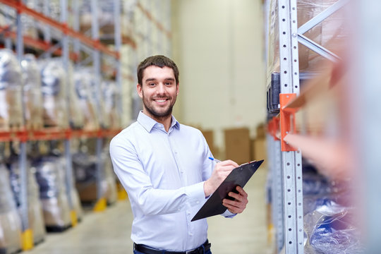 happy businessman with clipboard at warehouse