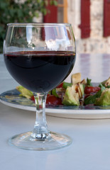 Glass of red wine with salad on an outside table