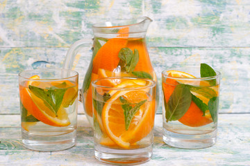 Lemonade with oranges and mint on a light wooden background. Mojito