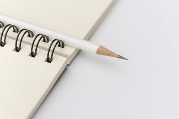 white pencil with blank notebook on white