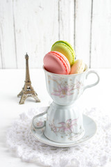 French macaroons in Cup on white wooden background