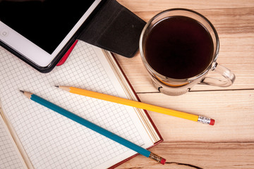 cup of espresso, checkered notebook and bun on wooden background