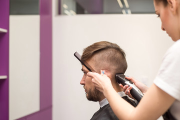 young man cuts hair in the barber shop