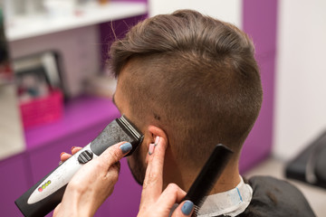 young man cuts hair in the barber shop