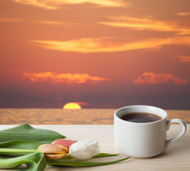 Tea cup with tulips on the wooden table opposite blurred backgro