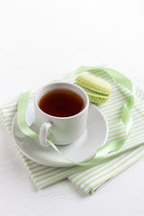Cup of tea and green French macaroons on a white wooden backgrou