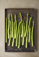 Fresh uncooked green asparagus on old rustic baking tray
