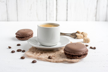 Coffee Cup and chocolate French macaroons on a white wooden back