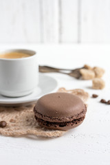 Coffee Cup and chocolate French macaroons on a white wooden back