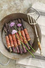 Purple asparagus wrapped with gammon in a skillet