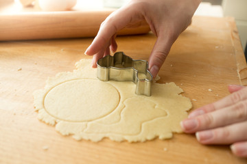 Closeup of woman cutting dough with metal form