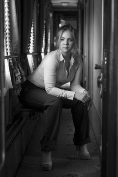 Black and white photo of stylish woman sitting in old train