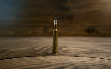 Closeup photo of bullet standing on old wooden desk