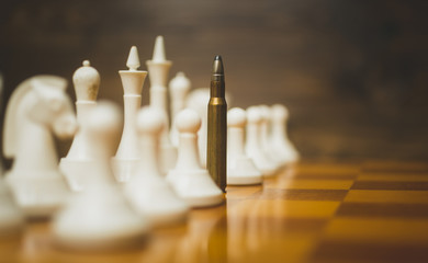Closeup photo of bullet in row of white chess pieces on wooden b © Kyrylo Ryzhov