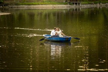 Newly married couple kissing on rowing boat in the middle of lak