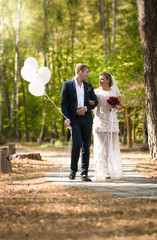 Fototapeta premium Just married couple with balloons walking at park