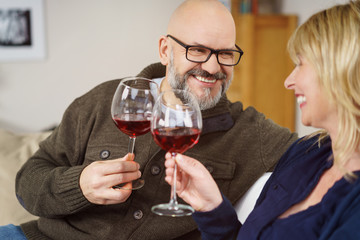 glückliches ehepaar stößt mit rotwein an