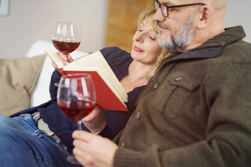 paar entspannt mit einem buch und einem glas rotwein