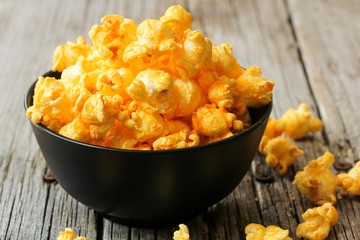 Cheese popcorn in a black bowl, selective focus - obrazy, fototapety, plakaty