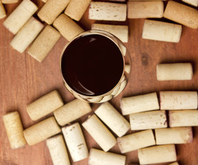 Glass of red wine with defocused corks around it