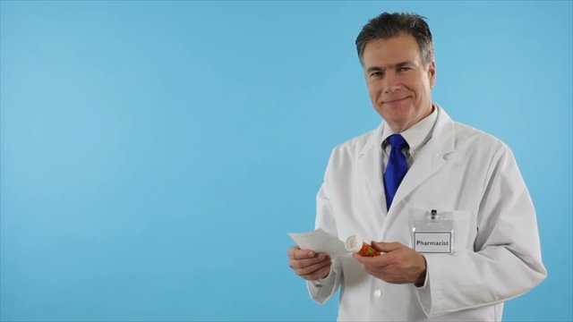 A friendly neighborhood pharmacist checks a prescription then smiles at the camera.