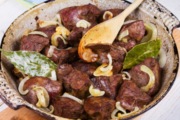 Sauteed liver with onions in pan.