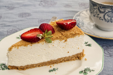 Piece of cheesecake in porcelain saucer and cup of coffee