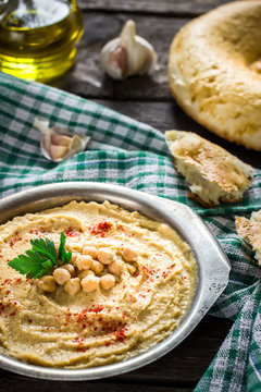 Hummus in metal bowl on  wooden table.