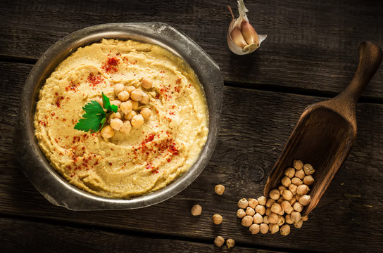 Hummus in metal bowl on  wooden table.