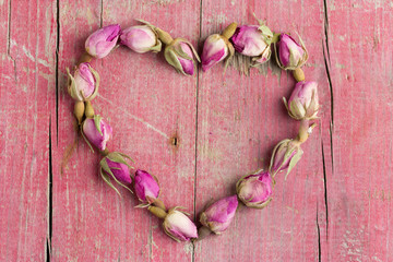Rose flowers in heart shape on old wooden background