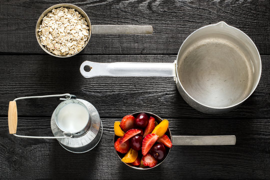 Utensils and ingredients for cooking oatmeal with milk and fruit