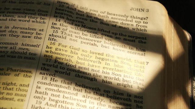 A wide shot of  the text of a Bible from chapter 3 verse 16 of the book of John.