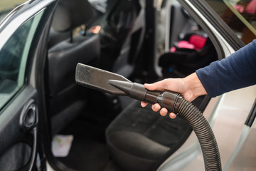 Closeup on auto car service cleaning and vacuuming the seats.
