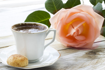 Turkish coffee with slices of pastry, peach-colored rose and book on the wooden table 