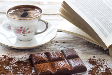 Turkish coffee with slices of chocolate and book on the wooden table 