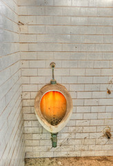 Filthy, stained urinal in the toilet of an abandoned prison.