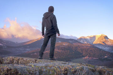 Fototapeta premium Man on top watching a beautiful sunrise in the sunny snowy mount