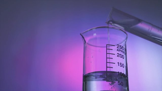 A water like substance is poured from a graded cylinder into a glass chemistry beaker containing a clear liquid. 