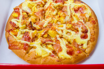 pizza with ham and pineapple in box.