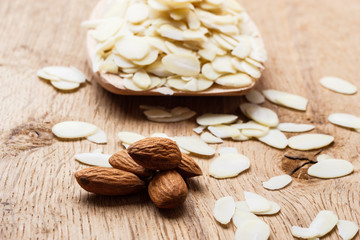 sliced and whole raw almonds on wooden surface