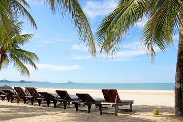 Beach chairs and coconut palm tree at the tropical beach, Pranburi, Thailand