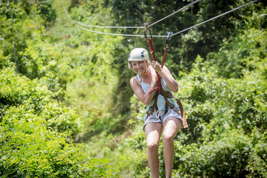 Beautiful woman riding a zip line in a lush tropical forest