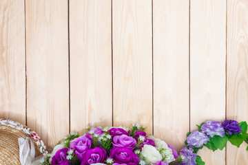 Fototapeta na wymiar Purple roses hat on wooden background. Top view.