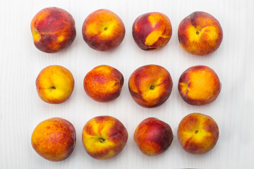Ripe peaches lying on white wooden surface, top view